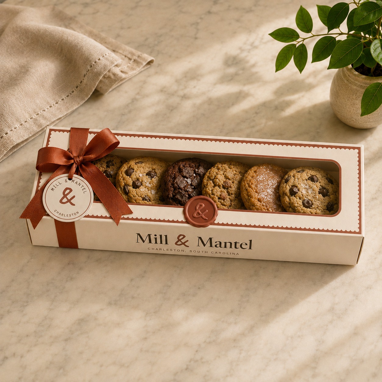 A long window box of cookies, ribbon-tied with a wax seal and a round hang tag